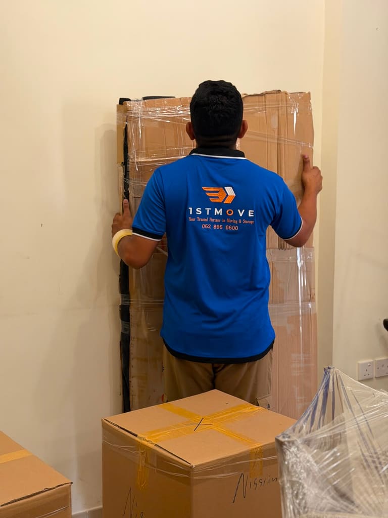A 1stMove crew member in branded uniform carefully wrapping furniture during a real Dubai relocation