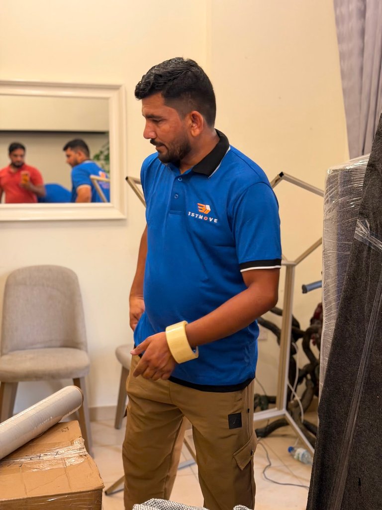 A real 1stMove crew member standing beside wrapped furniture during a home move