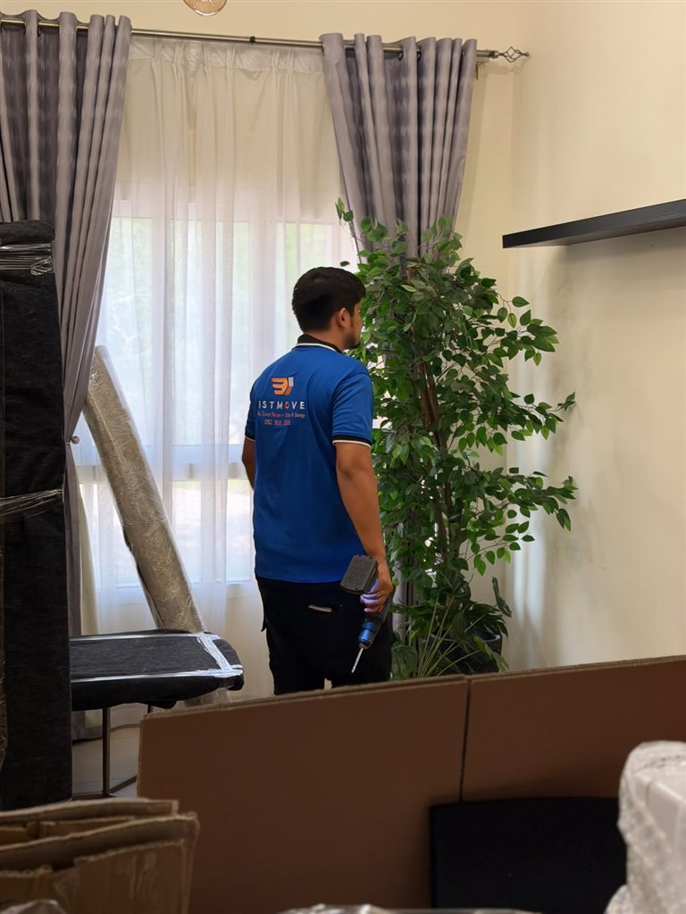 Real 1stMove crew member in a branded uniform disassembling furniture during a house move in Dubai