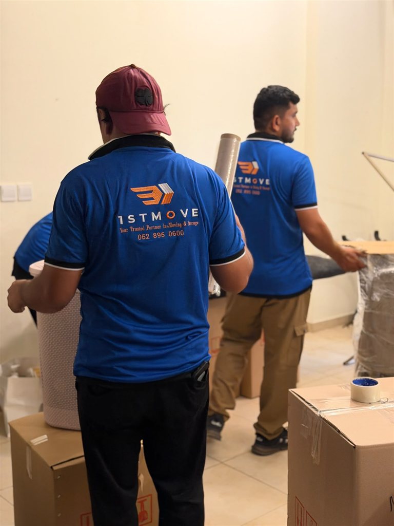 Real 1stMove crew members in branded uniforms taping and preparing boxes for an international shipment in Dubai