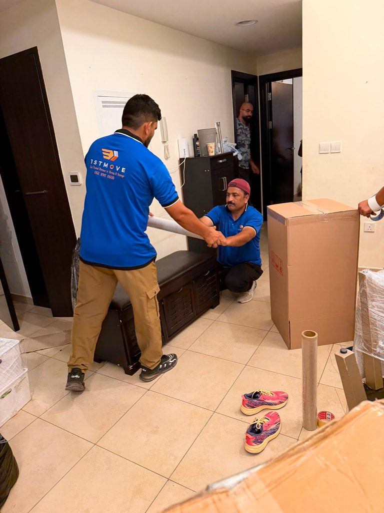 Two real 1stMove crew members carrying a wrapped bench together during an apartment move