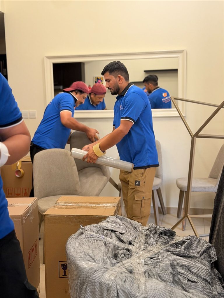 Real 1stMove crew member in a branded uniform wrapping furniture during an office relocation in Dubai