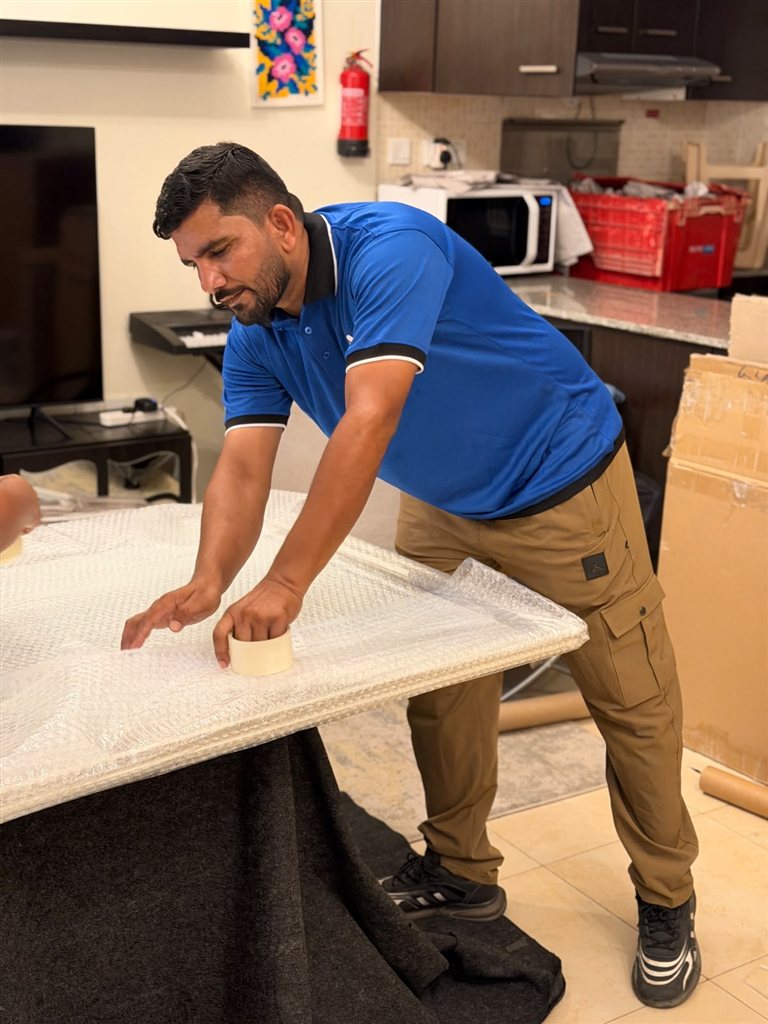 Real 1stMove crew member carefully bubble-wrapping and taping furniture inside a Dubai home